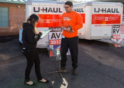 A woman signing a document with a man standing nearby.