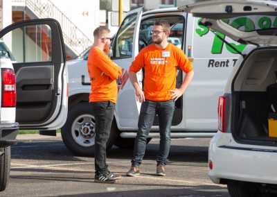 Two people interacting near a U-Haul cargo van.