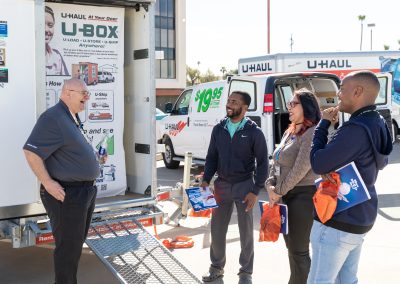 Four U-Haul employees talking in front of a U-Box container.