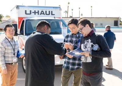 Several U-Haul employees reading a flyer.