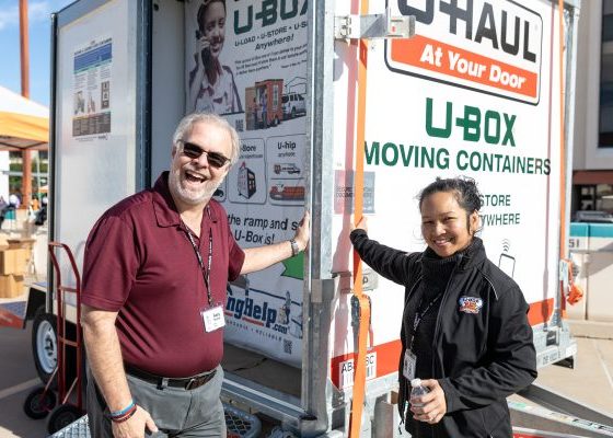 Two U-Haul employees posing in front of a U-Box container.